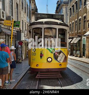 Tramway jaune, ligne 28, à un arrêt dans la vieille ville, touristes en attente, Lisbonne, Portugal Banque D'Images