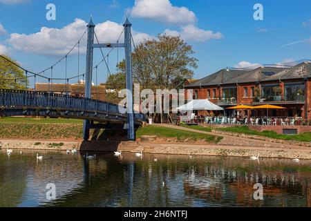 Détail du piéton de Cricklepit, pont suspendu au-dessus de la rivière exe avec les restaurants et les bâtiments de Riverside, un ciel bleu et des cygnes; Exeter, Devon. Banque D'Images