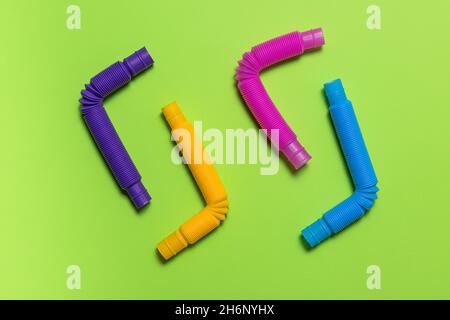 Quatre jouets colorés en tube pop bleu, rose, violet et jaune pour enfants sont inclinés à angle droit.Jeu de tubes en plastique anti-stress multicolores gaies Banque D'Images