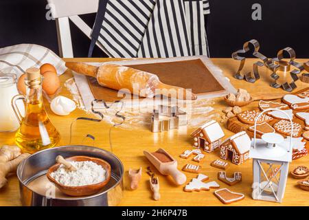 Maisons en pain d'épice de Noël et biscuits de différentes formes avec glaçage au sucre sur table en bois, gros plan avec attention sélective Banque D'Images