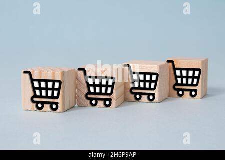 Cubes en bois avec les icônes de chariot sur un fond gris - concept de shopping Banque D'Images