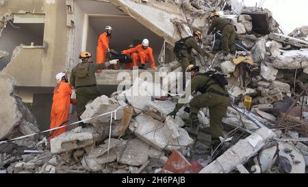 Des soldats israéliens de l'unité de secours du Commandement du front intérieur et des membres de l'équipe d'identification des victimes de catastrophes de Zaka traversent les décombres d'un bâtiment qui s'est effondré, puisqu'ils participent à un exercice de recherche et de sauvetage sur un grand site de démolition le 16 novembre 2021 à tel Aviv, Israël.Le forage Home Front a simulé une opération de recherche et de sauvetage se préparant à des scénarios qui pourraient détruire des bâtiments et piéger des citoyens à la suite d'un tremblement de terre majeur ou de barrages massifs de roquettes. Banque D'Images