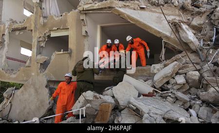 Des soldats israéliens de l'unité de secours du Commandement du front intérieur et des membres de l'équipe d'identification des victimes de catastrophes de Zaka extraient une victime simulée d'un bâtiment détruit lors d'un exercice de recherche et de sauvetage, dans un grand site de démolition le 16 novembre 2021 à tel-Aviv, Israël.Le forage Home Front a simulé une opération de recherche et de sauvetage se préparant à des scénarios qui pourraient détruire des bâtiments et piéger des citoyens à la suite d'un tremblement de terre majeur ou de barrages massifs de roquettes. Banque D'Images