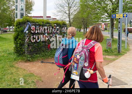 Saint-Jacques-de-Compostelle, Espagne; 19 avril 2019: Deux pèlerins femmes entrent dans la ville de Saint-Jacques-de-Compostelle avec un signe de la ville en arrière-plan.CAMI Banque D'Images