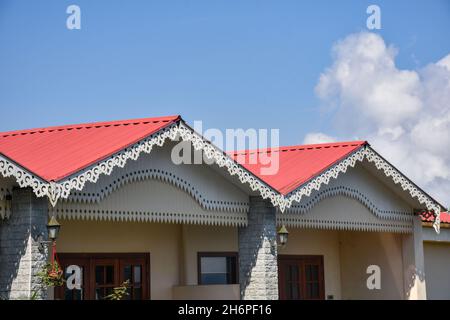 Magnifique toit métallique rouge alpin et ciel bleu nuageux Banque D'Images