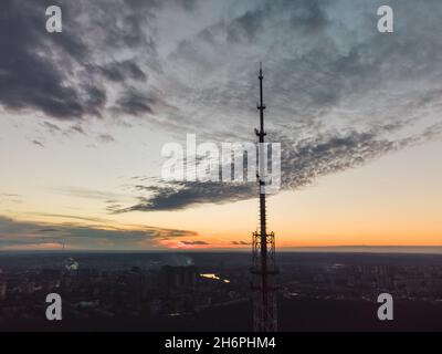 Coucher de soleil aérien en soirée vue sur la ville sur la silhouette sombre de l'antenne de la tour de télécommunication et le ciel nuageux pittoresque.Kharkiv, Ukraine Banque D'Images