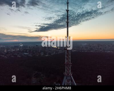 Coucher de soleil aérien vue en soirée sur la forêt avec une silhouette sombre d'antenne de tour de télécommunication et un ciel nuageux pittoresque.Kharkiv, Ukraine Banque D'Images