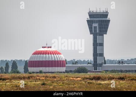 Tour de contrôle de l'aéroport international et dôme radar d'aviation ou bâtiment peint en bandes rouges et blanches dans terrain d'herbe sec avec ciel gris.Khar Banque D'Images