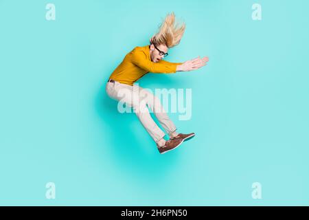 Pleine longueur profil photo de côté de jeune homme sauter vers le haut stupéfait surprise look vide isolé sur fond turquoise couleur Banque D'Images