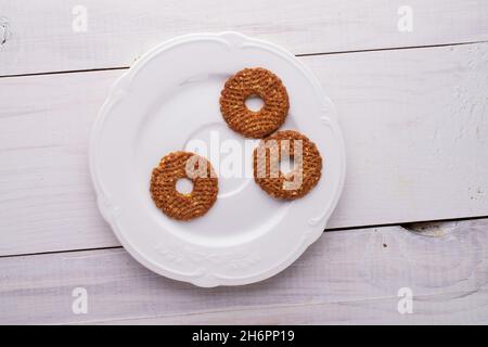 Trois petits gâteaux faits maison avec des noix dans une plaque en céramique blanche sur une table en bois, vue rapprochée, vue de dessus. Banque D'Images