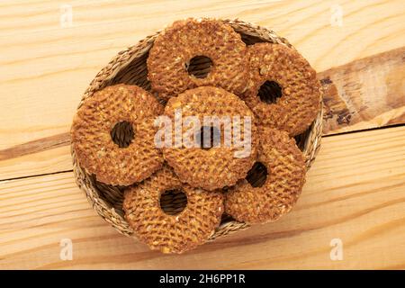 Plusieurs petits gâteaux fraîchement cuits avec des noix dans un bol de paille sur une table en bois, vue rapprochée, vue de dessus. Banque D'Images