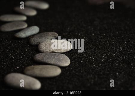 les petits cailloux de mer sont disposés sur un fond noir Banque D'Images