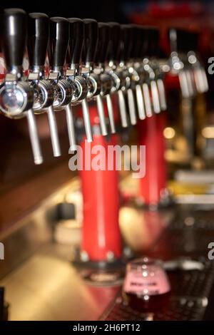 Main de barman versant une grande bière lager dans le robinet.Verser de la bière pour le client.Vue latérale d'un jeune barman qui verse de la bière tout en se tenant au bar Banque D'Images