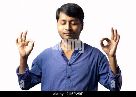 Un jeune Indien en robe bleue montrant calme et méditation sur fond blanc Banque D'Images