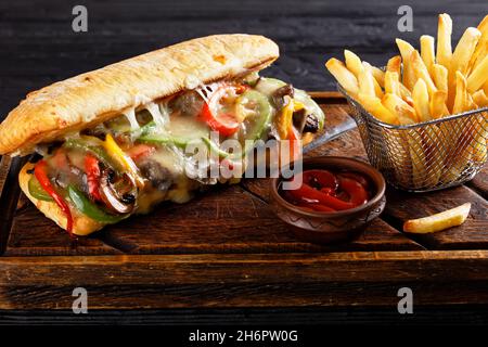 Sandwich au steak au fromage de Philadelphie avec bœuf rôti, poivre, oignon caramélisé, champignons et fromage fondu avec frites de pommes de terre Banque D'Images