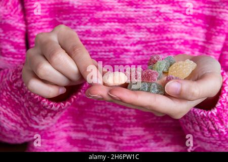 Femme tenant des bonbons, photo de gros plan de bonbons en gelée dans la main de fille. Banque D'Images