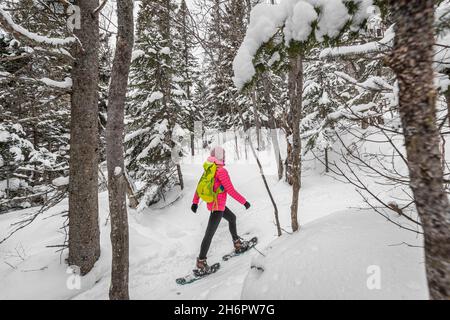 Raquette sur les gens dans la forêt d'hiver avec des arbres couverts de neige le jour de neige.Femme en randonnée dans la neige randonnée en raquettes vivant en plein air actif sain Banque D'Images