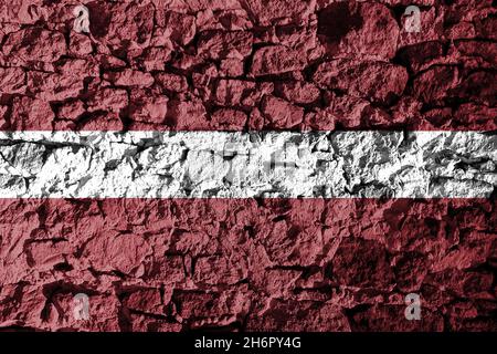 Drapeau letton représenté sur un mur de pierre.La texture de la pierre se fond parfaitement avec les couleurs de la bannière Banque D'Images