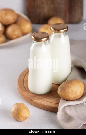 Bouteilles de lait à base de plantes végétaliennes.Boisson sans produits laitiers et tubercules de pommes de terre sur table grise - image Banque D'Images