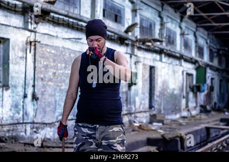 Jeune rebelle dans un hall d'usine abandonné avec une barre de métal dans sa main.Mise au point sélective. Banque D'Images