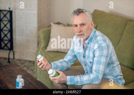Homme dans une chemise à carreaux contenant des compléments alimentaires Banque D'Images