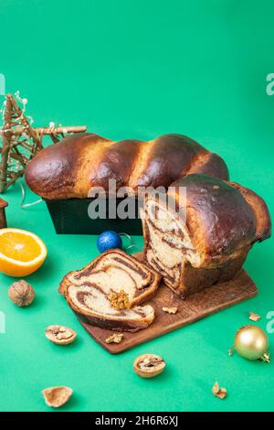 Pain sucré traditionnel roumain appelé 'cozonac', sur fond vert avec des noix et des décorations de Noël Banque D'Images