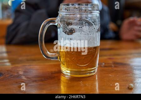 Bière artisanale isolée au miel froid avec mousse dans une tasse, sur une table en bois.Horizontale.Arrière-plan flou Banque D'Images