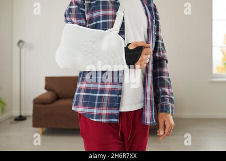 Un homme qui a blessé son bras, sa main, son poignet ou son coude porte une bride et une élingue de soutien Banque D'Images