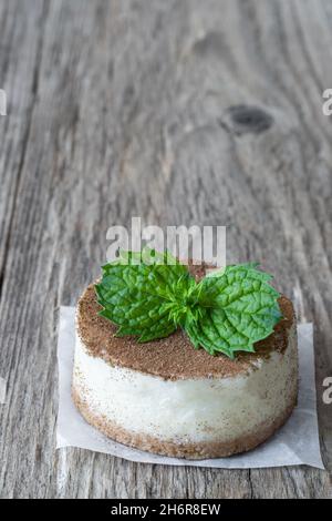 mini-cheesecake décoré de feuilles de menthe sur une table rustique en bois Banque D'Images