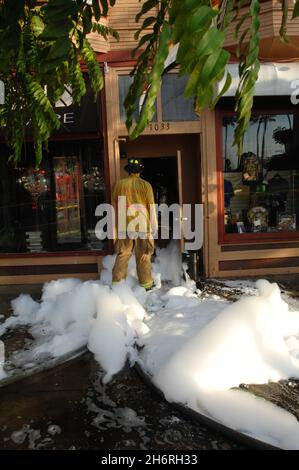 La mousse de lutte contre le feu coule sur le trottoir après application à un feu de structure sur University Avenue, à San Diego, Californie Banque D'Images