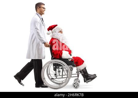 Prise de vue en profil d'un médecin poussant le père noël dans un fauteuil roulant isolé sur fond blanc Banque D'Images