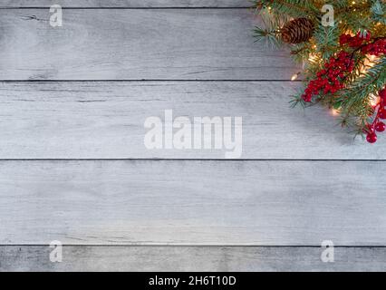 Mise en page créative des fêtes d'hiver.Fait de lumières d'arbre de Noël, de pin, de baies rouges et de cônes sur des panneaux de bois blancs.Concept nouvel an et Noël. Banque D'Images