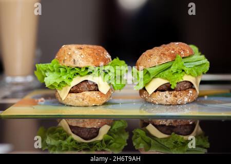 Sandwich avec côtelette, fromage et salade verte sur une assiette dans la cuisine. Sandwich à la maison. Le concept de nourriture saine et malsaine. Banque D'Images