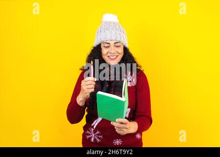 Femme latine tenant des bougies de noël et chantant des chants de chants sur fond jaune au Mexique Amérique latine Banque D'Images