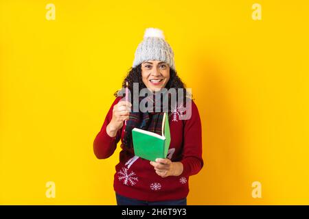 Femme latine tenant des bougies de noël et chantant des chants de chants sur fond jaune au Mexique Amérique latine Banque D'Images