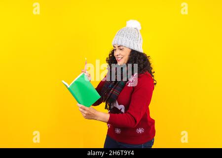 Femme latine tenant des bougies de noël et chantant des chants de chants sur fond jaune au Mexique Amérique latine Banque D'Images