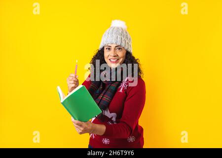 Femme latine tenant des bougies de noël et chantant des chants de chants sur fond jaune au Mexique Amérique latine Banque D'Images