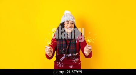 Femme hispanique adulte tenant des lumières pétillantes de noël pour la posada mexicaine à noël sur fond jaune au Mexique Amérique latine Banque D'Images