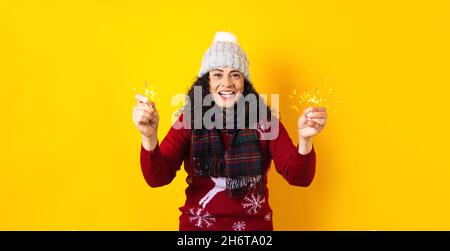 Femme hispanique adulte tenant des lumières pétillantes de noël pour la posada mexicaine à noël sur fond jaune au Mexique Amérique latine Banque D'Images