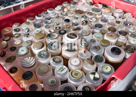 Boutons de toutes formes, matériaux, tailles et couleurs dans des tubes en plastique dans un stalle de marché.Concentrez-vous sur les boutons situés en bas, à l'avant de la boîte Banque D'Images