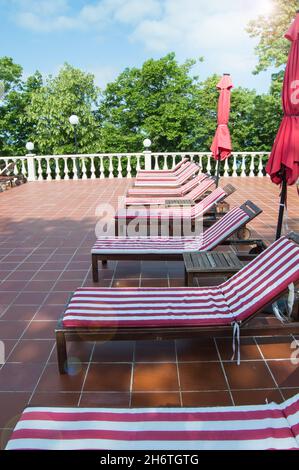 Chaises longues en bois vides avec matelas à rayures rouges et blanches.Loisirs de luxe en extérieur, photo verticale. Banque D'Images