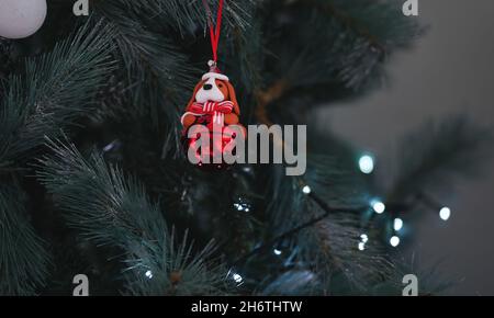 Décoration de Noël avec un chien orné d'un noeud rouge accroché à un arbre de Noël Banque D'Images