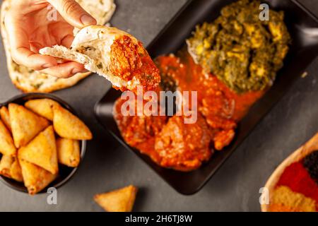 Une femme mange une délicieuse cuisine indienne avec divers plats.Elle plonge le pain naan dans le curry.Concept pour manger une cuisine asiatique ou un restaurant avec une var Banque D'Images