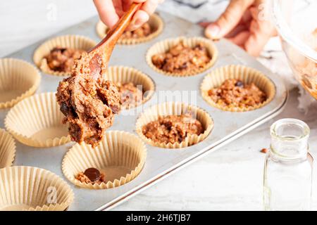 fabrication de délicieux fruits et cupcake aux noix sur fond de comptoir en marbre blanc.Moule à muffins avec doublure, ingrédients et ustensiles.Une femme est Banque D'Images