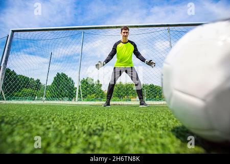 Homme de football joueur gardien de but attrapant le ballon à la pénalité. Banque D'Images