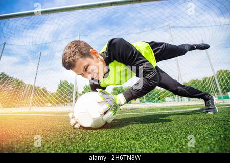 Action football homme joueur gardien de but attrapant le ballon à la pénalité. Banque D'Images