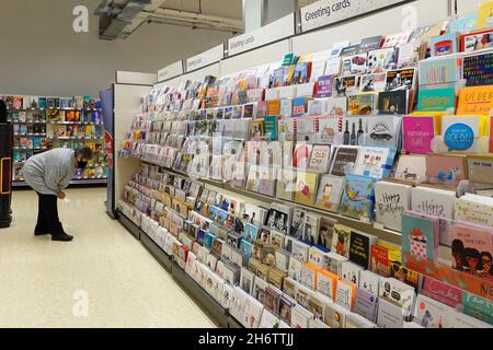 Femme mature senior shopper dans masque de visage shopping dans un magasin de supermarché Sainsburys navigation dans l'allée pour sélectionner le message sur carte de voeux rack Angleterre Royaume-Uni Banque D'Images