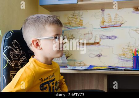 Retour à l'école.Petit garçon fatigué faisant des devoirs à la maison avec sac à dos plein de livres, crayons.Kid est le dessin, l'écriture et la peinture.École, à distance Banque D'Images