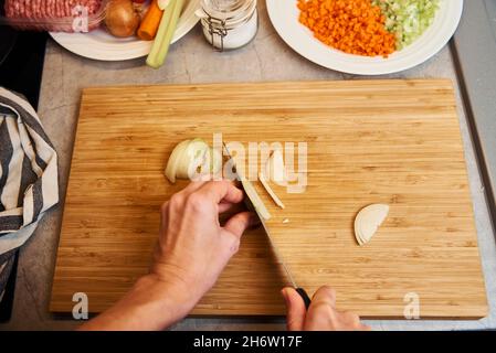 Une femme avec un couteau coupe l'oignon sur des tranches pour la cuisson Banque D'Images