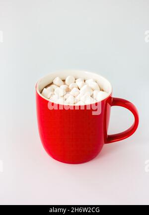 Tasse rouge remplie de chocolat chaud et mini guimauves isolées sur blanc.Vue en angle. Banque D'Images